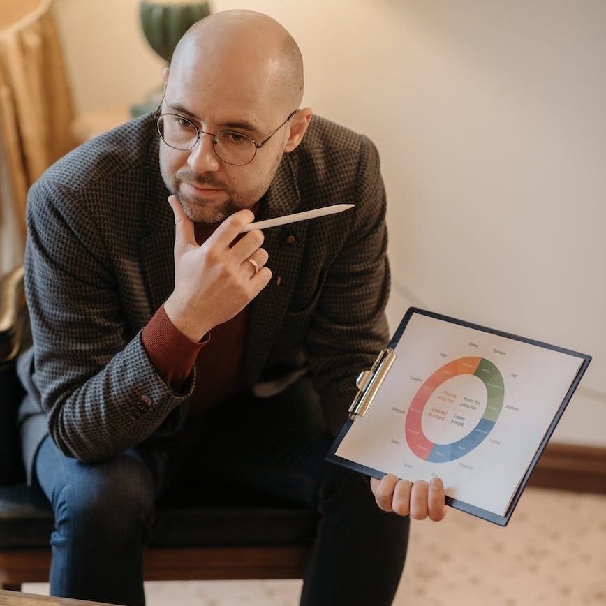 pensive man sitting on chair holding a clipboard and pen