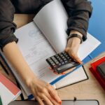 person holding black calculator while using laptop